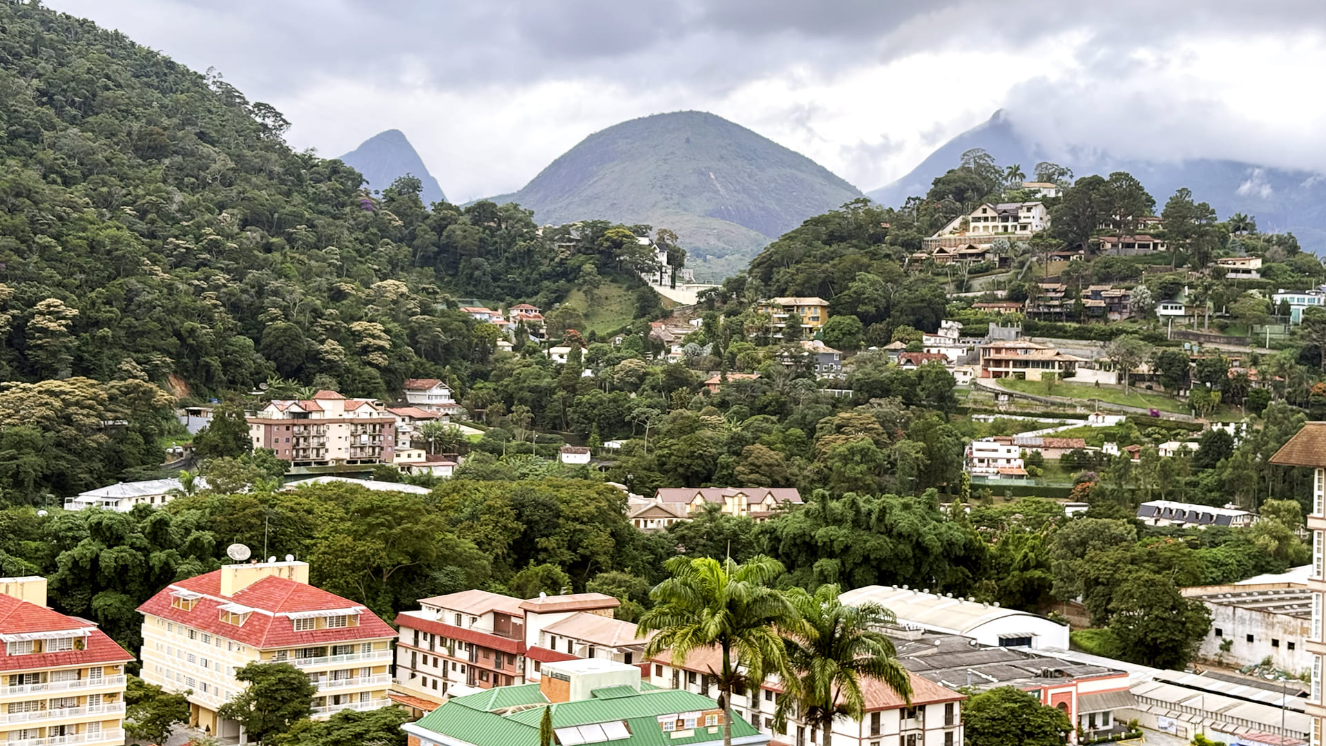 Vista panorâmica de Itaipava com casas entre vegetação e montanhas, em contraste com o perfil urbano de origem dos compradores